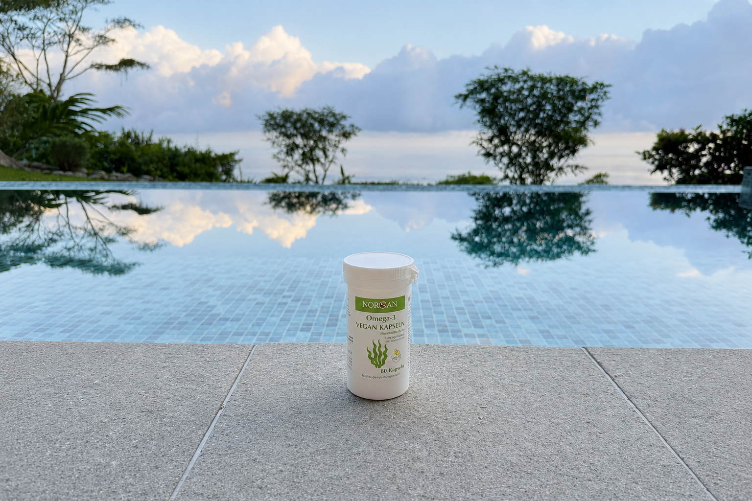 NORSAN Omega-3 Vegan Kapseln vor einem Pool während einer Reise